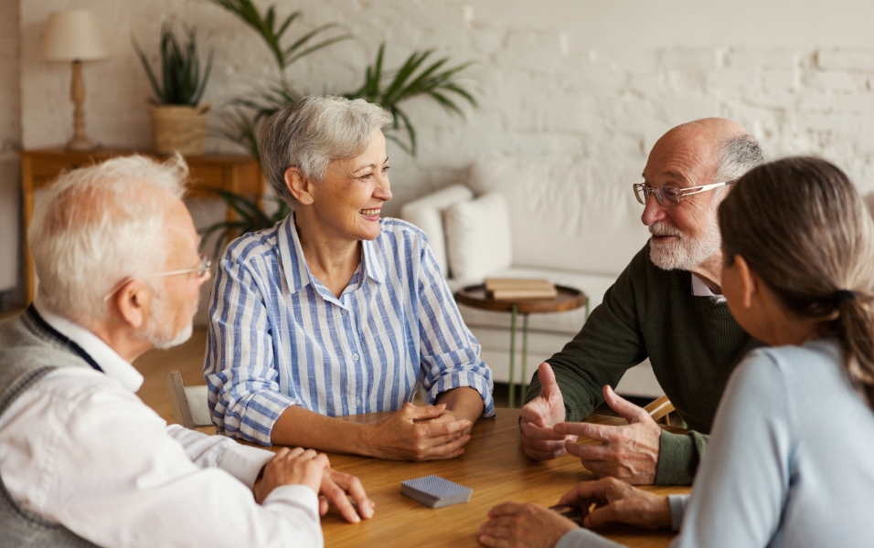 Immagine di un gruppo di anziani sorridenti intorno a un tavolo.